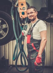 Poster - Serviceman in a car workshop