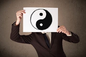 Wall Mural - Businessman holding a paper with a yin-yang on it in front of hi