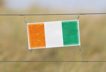 Wall Mural - Border fence - Old plastic sign with a flag