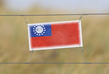 Wall Mural - Border fence - Old plastic sign with a flag