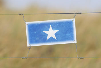 Wall Mural - Border fence - Old plastic sign with a flag