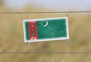 Wall Mural - Border fence - Old plastic sign with a flag