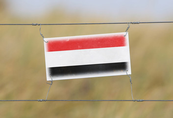 Wall Mural - Border fence - Old plastic sign with a flag