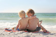 Young Brothers Sitting on Beach By Ocean with Arms Around Each O