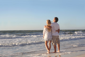 Happy Couple Looking out Over Ocean While Walking on Beach