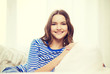 © Syda Productions - smiling teenage girl sitting on sofa at home