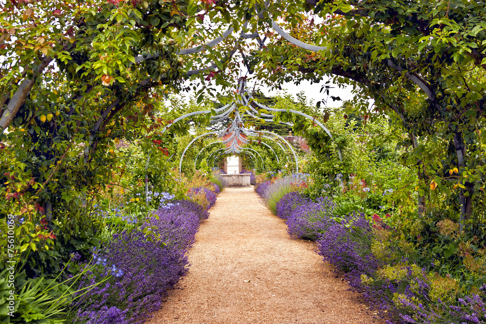 Colourful English summer flower garden with a path under archway - obrazy, fototapety, plakaty 