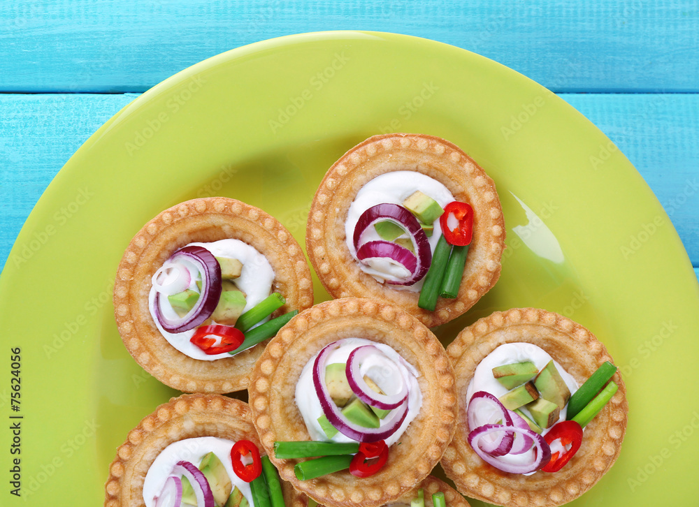Tartlets with greens and vegetables with sauce on plate on