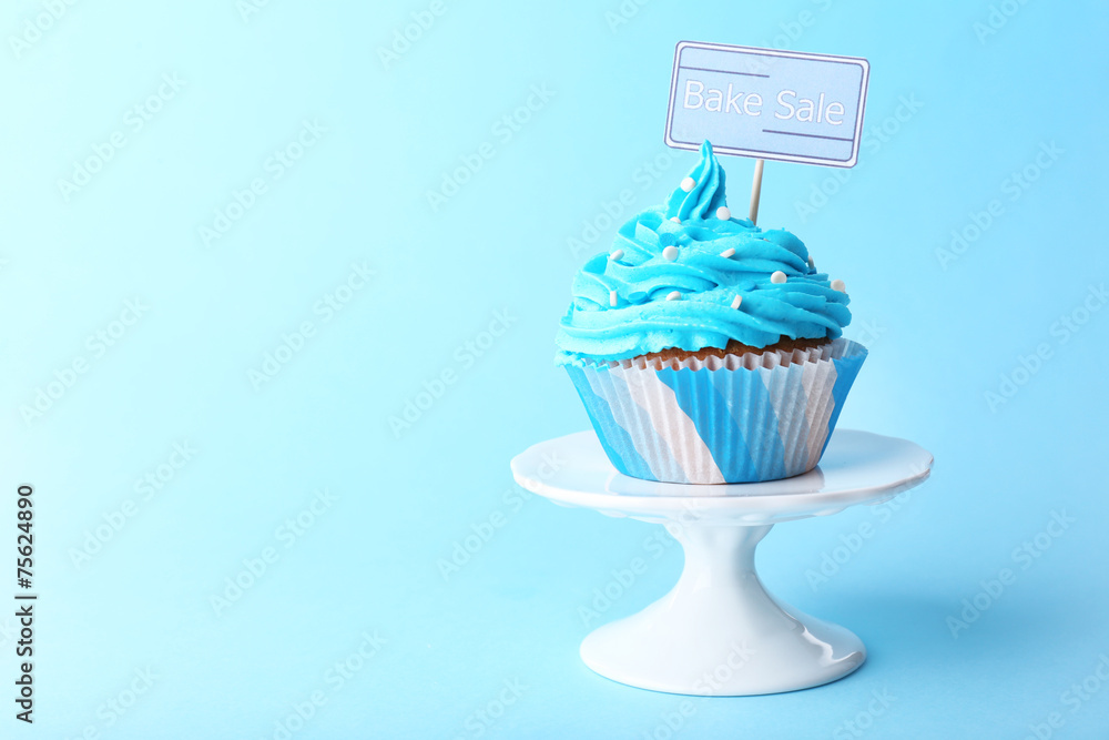 Delicious cupcake with inscription on blue background