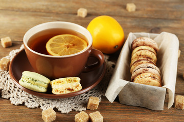 Canvas Print - Colorful macaroons with cup of tea on wooden background