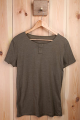 Wall Mural - Male t-shirt on hanger on wooden wall background