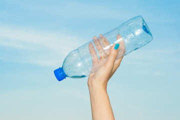  Woman hand holding a bottle of water in the sky.