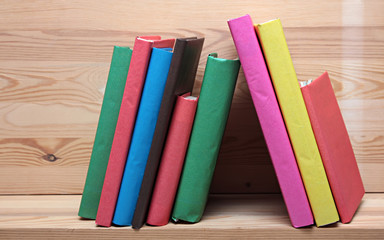 Books on wooden shelf close-up. No labels, blank spine.