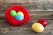 Colorful easter eggs in red nest on wooden background
