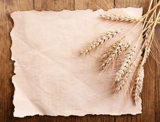 Poster - Spikelets of wheat with paper on wooden background