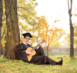 Wall Mural - Graduate student playing acoustic guitar in park