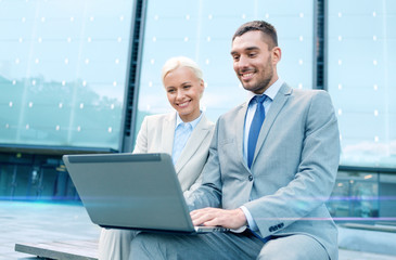 Canvas Print - smiling businesspeople with laptop outdoors