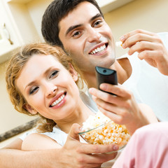 Wall Mural - Couple eating popcorn and watching TV