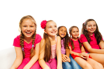 Beautiful small girls sit together on white sofa