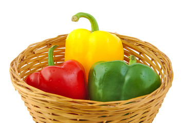 Wall Mural - Green, red and yellow fresh peppers on a wicker basket isolated