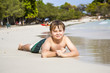 © travelview - boy lies at the sandy beach and enjoys the fine warm sand