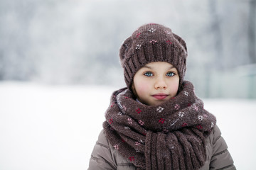 Happy little girl on the background of a winter park