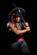 © kanzefar - Muscular man in a pirate hat and sword on a black background