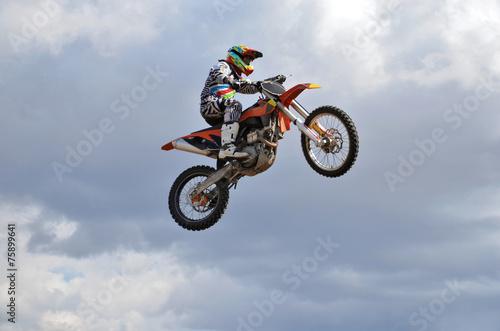 Tapeta ścienna na wymiar Rider by motorcycle MX flies over the hill against the blue sky