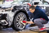 Fototapeta Na sufit - Man worker washing car's alloy wheels on a car wash