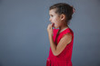 © maxximmm - Teen girl fingers in his mouth red dress on a gray backgrou