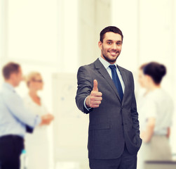 Wall Mural - handsome buisnessman showing thumbs up in office