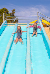 Wall Mural - Cute girls on water slide at aquapark during summer holiday