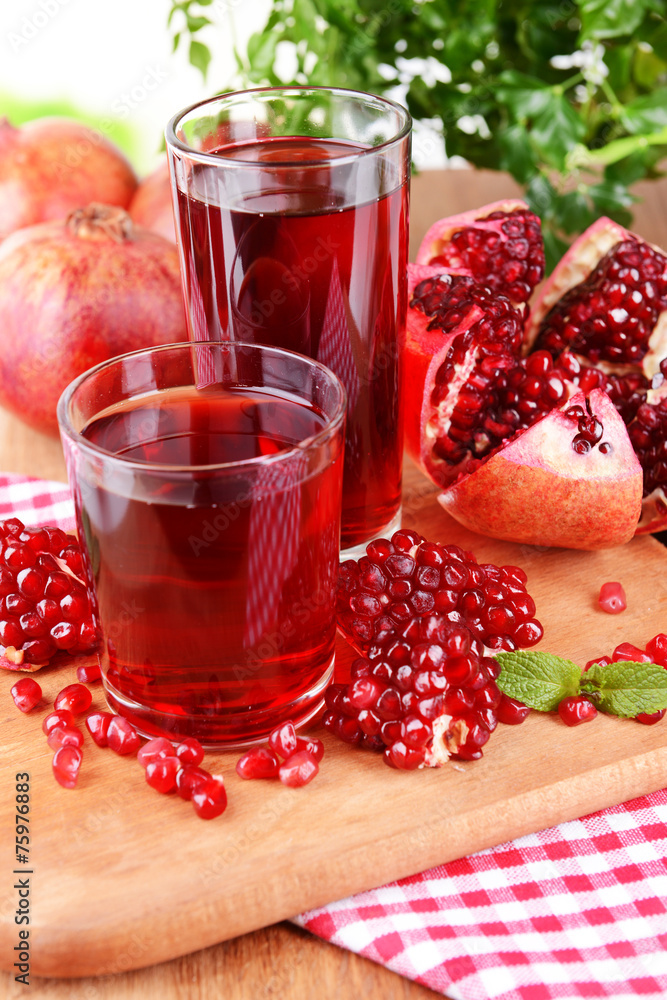 Ripe pomegranates with juice on table close-up
