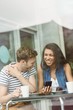 © WavebreakmediaMicro - Smiling friends with chocolate cake using smartphone