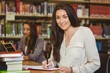 © WavebreakMediaMicro - Smiling pretty brunette student writing in notepad