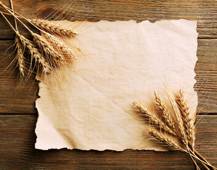 Poster - Spikelets of wheat with paper on wooden background