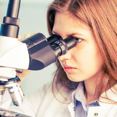 Wall Mural - Scientist young woman using a microscope in a science laboratory