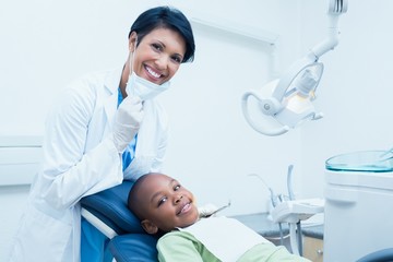 Portrait of smiling female dentist examining boys teeth