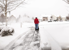Woman Using A Snowblower To Clear A Driveway During Snowstorm