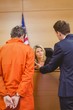 © WavebreakMediaMicro - Lawyer and judge speaking next to the criminal in handcuffs