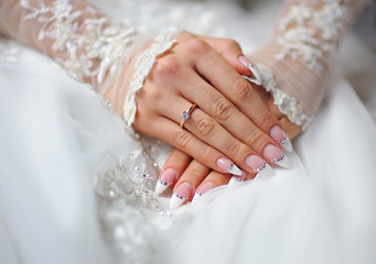 hands of a bride with a ring and a wedding manicure