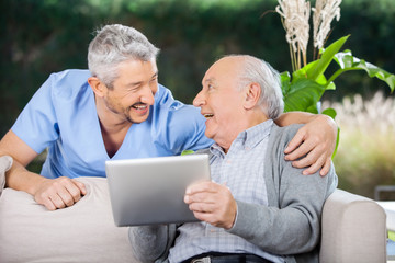 Wall Mural - Laughing Caretaker And Senior Man Using Tablet Computer