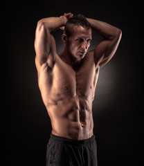 Wall Mural - Muscular man on black background