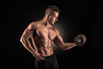 Wall Mural - Muscular man with dumbbells on black background