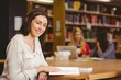 © WavebreakMediaMicro - Smiling student sitting at desk reading text book