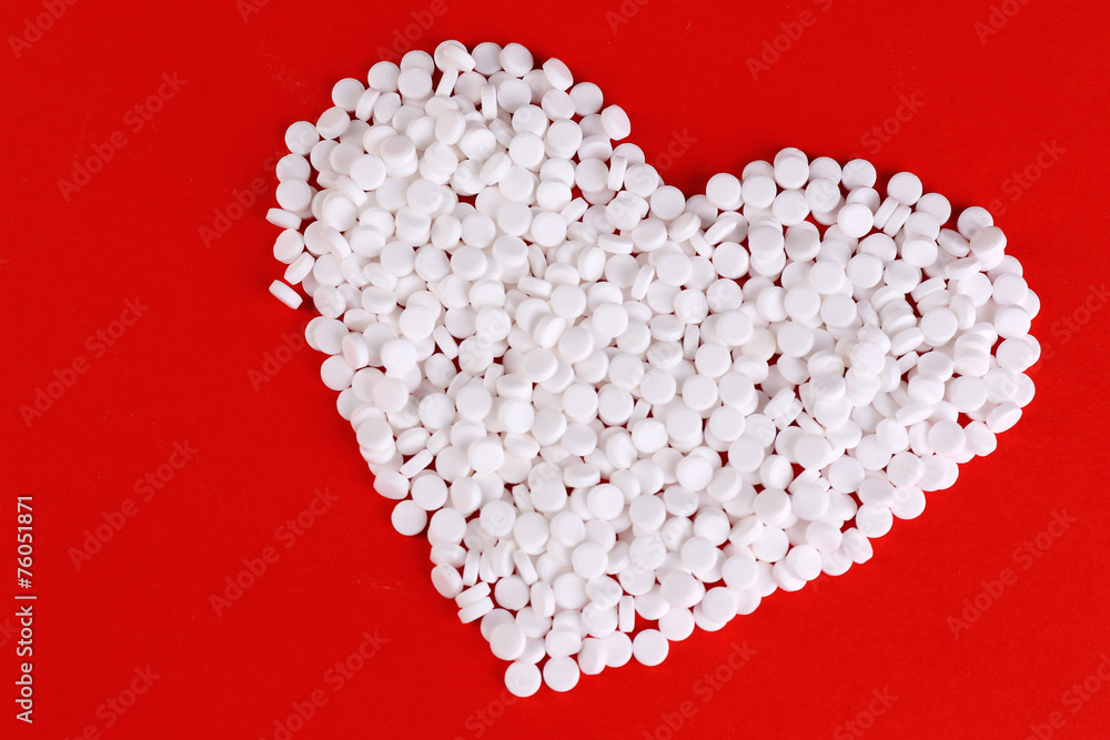 Heart of pills on red background