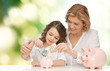 © Syda Productions - mother and daughter putting money to piggy banks