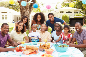 Multi Generation Family Enjoying Meal In Garden Together