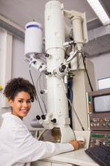 Wall Mural - biochemistry student using large microscope and computer