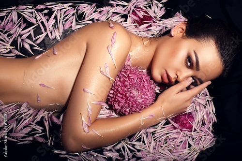 Obraz w ramie beautiful woman lying in petals of chrysanthemum in bathtub